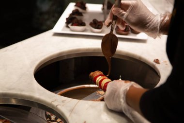 Çikolata üreticisi erimiş çikolataya çilek bandırıyor.