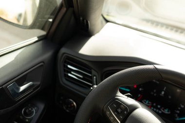 Sol tarafında kontrol paneli olan siyah deri bir direksiyon.