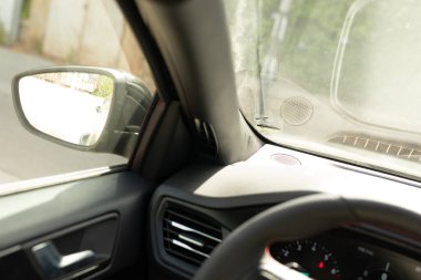 Yan aynası sokağı yansıtan bir arabanın içi.