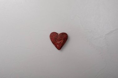 Kırmızı bir kalp beyaz bir zeminde oturur.