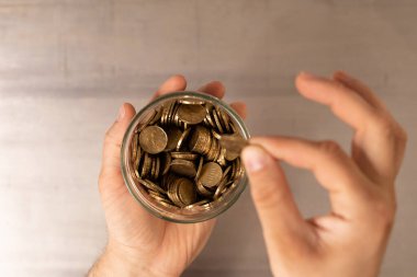 Bozuk para dolu bir kavanozu tutan bir el bir tane daha eklemek üzere.