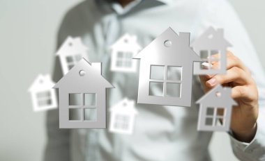 Adam gayrimenkul yatırımını ve ev mülkiyetini temsil eden evler tutuyor