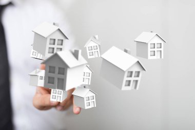 Emlak kavramını temsil eden minyatür evlerle el ele.