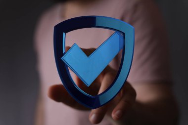 Üzerinde kontrol işareti olan bir kalkanı tutmak, iş güvenliği kavramı