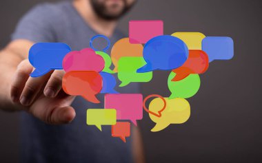 Dijital iletişimi ve sosyal medya etkileşimini temsil eden konuşma baloncuklarına uzanan adam