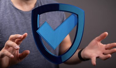 Elinde mavi kalkan sembolü olan adam güvenlik ve koruma kavramını temsil ediyor.