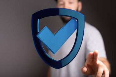 Güvenlik ve veri korumasını simgeleyen dijital kalkan simgesine dokunan adam