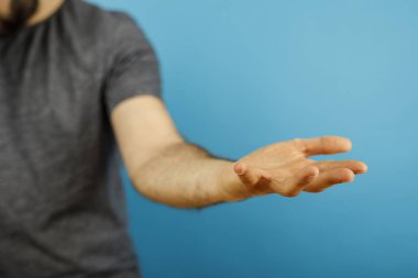 Konsept görüntü için mavi arkaplanda boş el teklif eden adam