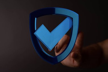 Güvenliği simgeleyen işaretli bir kalkanı tutan el.