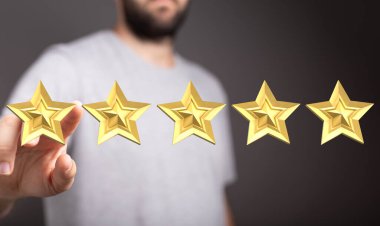 Derecelendirme konsepti, beş altın yıldız ve onları gösteren bir el.