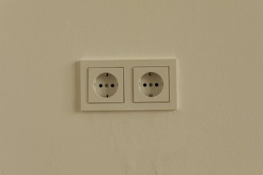 Krem bir duvarda iki beyaz elektrik prizi