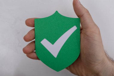 El ele tutuşan yeşil kalkan işaretli: onay, güvenlik, koruma konsepti