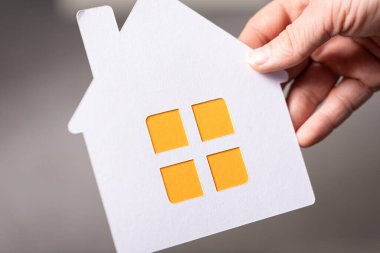 Elinde kağıt ev kesimi olan kişi