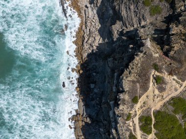 Çarpışan dalgalarla engebeli bir kıyı şeridinin havadan görüntüsü