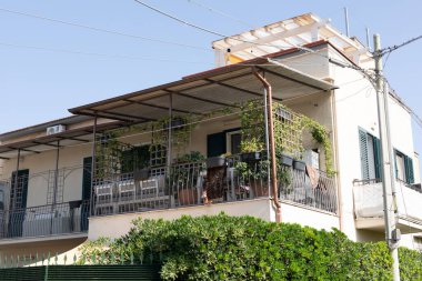 Sarmaşıklarla süslenmiş, balkonu olan beyaz bir bina.