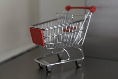 Masadaki minyatür alışveriş arabası perakende ve alışveriş konseptini temsil ediyor.
