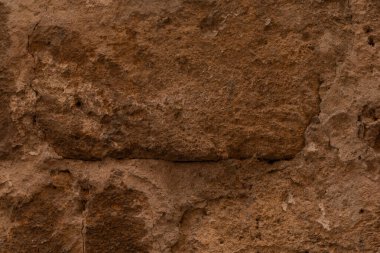 Çatlak ve pürüzlü dokuları olan eskimiş taş bir duvar.