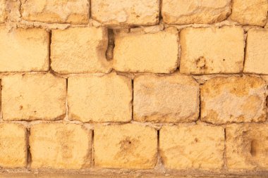 Sıcak sarı renkli, yıpranmış bir taş duvar.