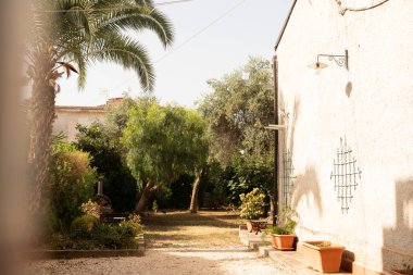 Bir patika, yemyeşil bir bahçeden geçerek beyaz bir buile doğru gidiyor.