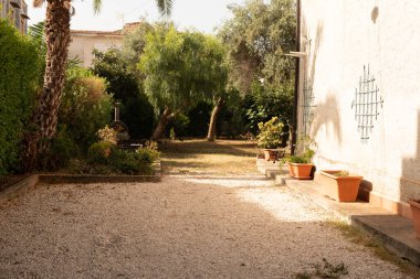 Çakıl yolu ve terakotta saksısı olan güneşli bir avlu.