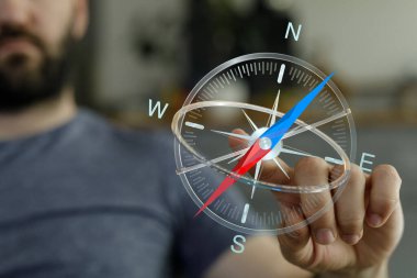 Adamın elinde pusula, yön bulma, keşif ve yön kavramı var.