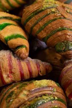 Fıstıklı ve kırmızı jöleli çeşitli renkli kruvasanlar. Fırın, kahvaltı, yemek fotoğrafçılığı..