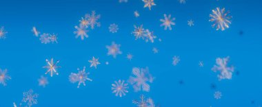 Açık mavi gökyüzüne düşen kar tanelerinin güzel bir görüntüsü, büyülü bir kış harikalar diyarı yaratıyor..