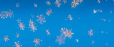 Mavi gökyüzüne düşen kar taneleri ile soyut bir arkaplan. Yumuşak odak rüya gibi ve tuhaf bir atmosfer yaratır..