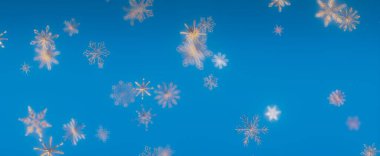 Kış harikalar diyarının özünü yakalayan canlı mavi gökyüzüne zarif bir şekilde düşen kar tanelerinin büyüleyici bir görüntüsü..