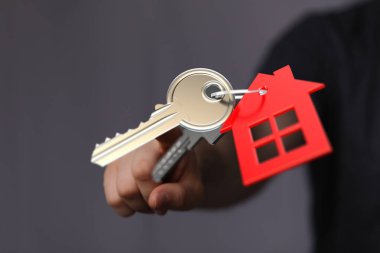 Kırmızı ev, ev sahipliği, ipotek ve gayrimenkul konseptiyle el ele tutuşmanın anahtarı.