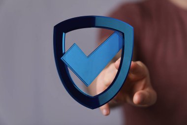 Güvenlik sembolü işaretli bir kalkanı tutan el.