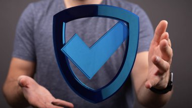 Elinde mavi kalkan sembolü tutan adam koruma ve güvenliği gösteriyor.