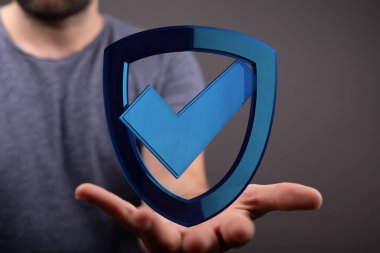 Güvenlik ve onay işaretli mavi kalkan sembolü tutan adam.