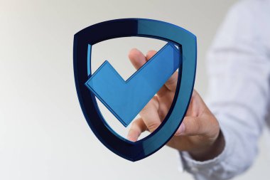 Güvenlik ve korumayı temsil eden işaretli bir kalkanı tutan kişi..