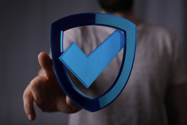 Güvenlik ve koruma için mavi kalkana dokunan bir adam var.