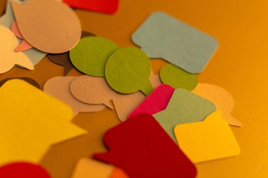 Sarı arkaplana saçılmış renkli konuşma baloncukları.