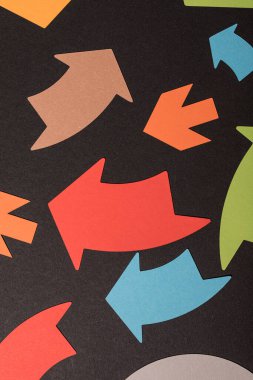 Siyah arkaplanda farklı yönleri gösteren renkli kağıt okları