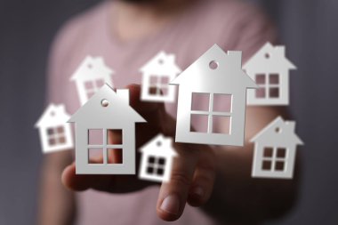 Yüzen kağıt evlere dokunan kişi, gayrimenkul yatırım konsepti.