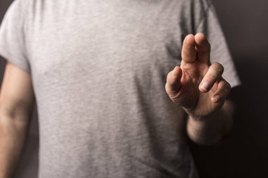 Elini bir objeye doğru gösteren kişi, açık gri gömlekli.