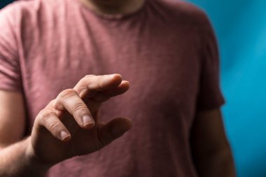 Adamın eli bulanık mavi bir arkaplanı işaret ediyor.