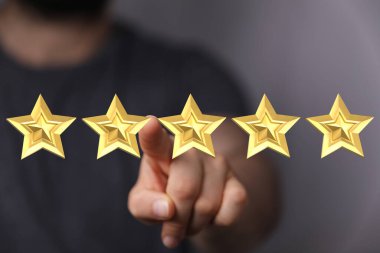 Beş altın yıldızı işaret eden kişi mükemmel derecelendirme ya da gözden geçirme yapıyor