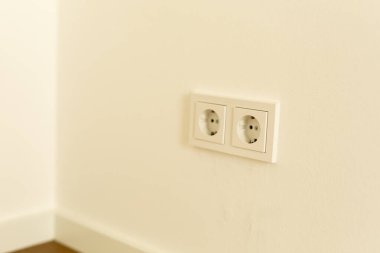 Beyaz bir duvarda iki boş elektrik prizi.