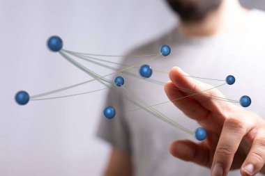 Bir adamın eli birbirine bağlı kürelere doğru uzanıyor.