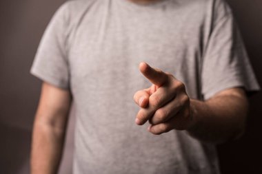 Parmağını parmağıyla gösteren ve gri gömlek giyen bir adam.