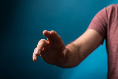 Adamın eli bulanık mavi arka planla izleyiciye doğru uzanıyor.