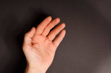 Koyu siyah bir arkaplan karşısında insan elini açık tut.