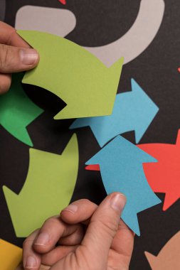 Renkli kağıt okları düzenleyen eller, yön ve hareket kavramı