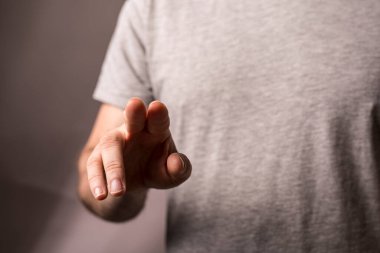 Adamın eli gri tişört arka planına dokunuyor ya da işaret ediyor..