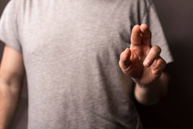 Elini bir objeye doğru gösteren kişi, açık gri gömlekli.