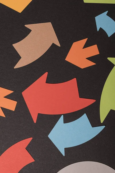 Siyah arkaplanda farklı yönleri gösteren renkli kağıt okları